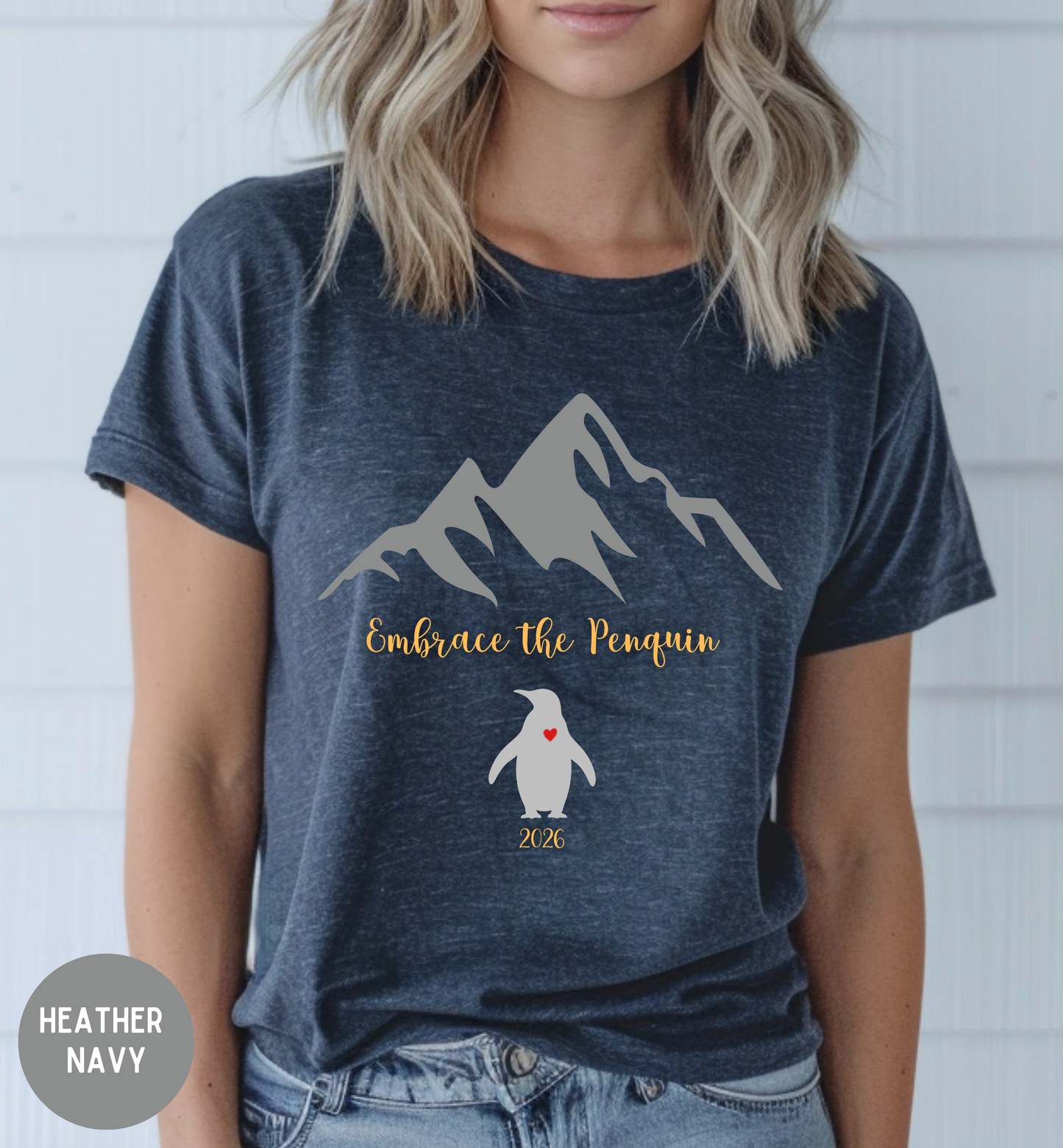Person wearing a navy t-shirt with mountain and penguin design, text 'Embrace the Penguin 2020'.
